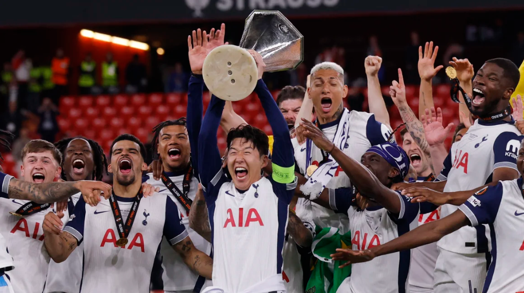 An image of Tottenham team celebrating with the Europa League trophy on the field.